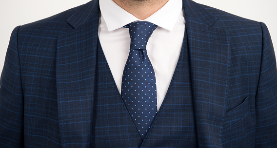 Tie goes inside vest. Vested three-piece suit worn with tie. Necktie collection. Fashion accessory. Formal style. Stylish mans wardrobe. Social occasion. Business meeting. Knot tied with extra care.