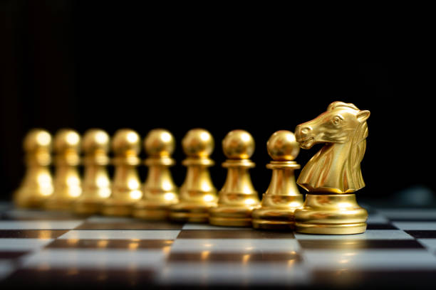 istock Gold knight chess piece stand with pawn on black background (Concept of teamwork, management) 1295592860
