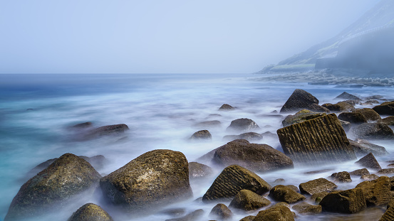 Beach of large rocks with fog and long exposure in the north of Spain europe