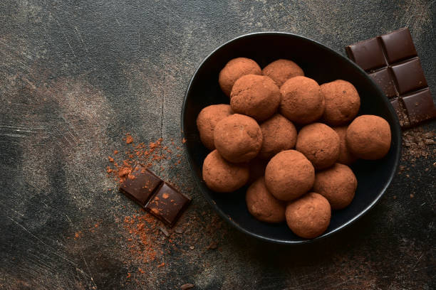 Homemade delicious chocolate rum truffles Homemade delicious chocolate rum truffles in a black bowl on a dark slate, stone or concrete background. Top view with copy space. chocolate truffle stock pictures, royalty-free photos & images
