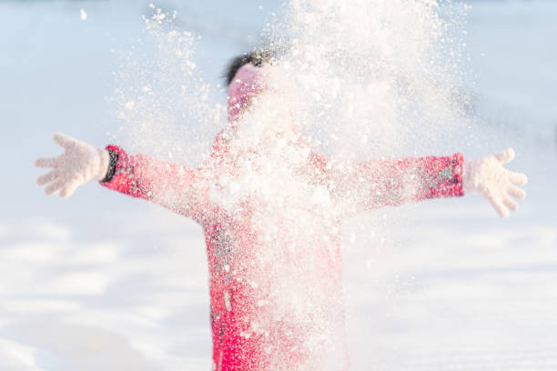 istock Winter, a girl plays outside throwing snow up 1295596384