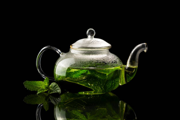 Teapot with brewed mint tea on a black background stock photo