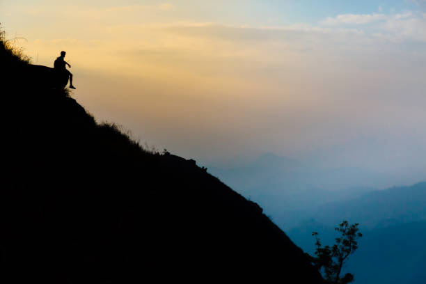 istock Mountaineer watching the sunrise sitting on a rock 1295596733