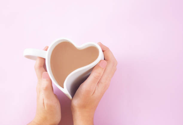 istock hands hug a heart-shaped cup with coffee 1295599167