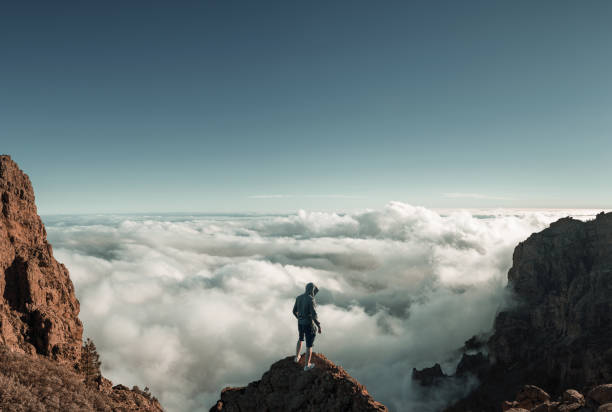 istock Man standing on the mountain peak above the clouds 1295600795