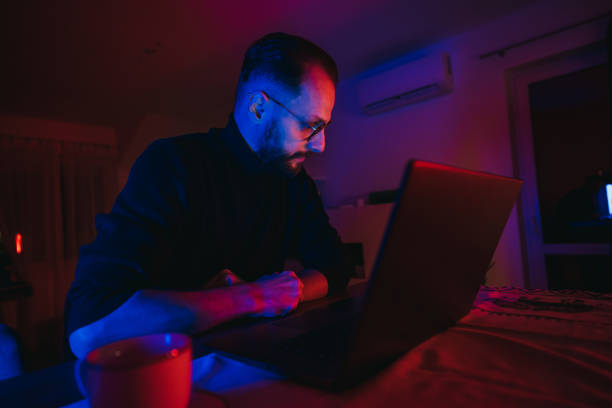 istock Man working on laptop at home office at night 1295603084