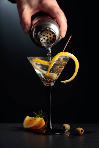 istock Dry martini with lemon peel and green olives on a black background. 1295606026