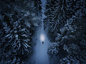 Lonely man walking through the forest during the winter night