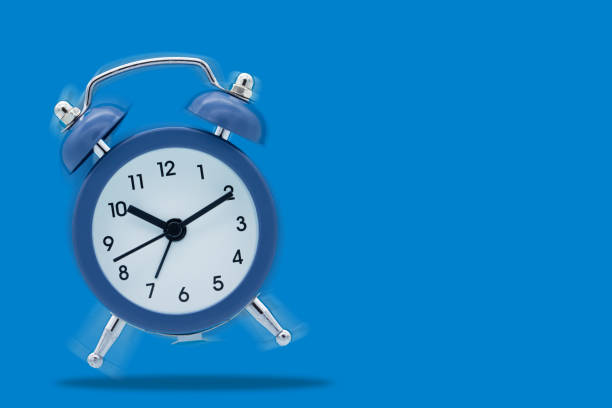 istock Classic alarm clock ringing isolated on blue background. 1295608253