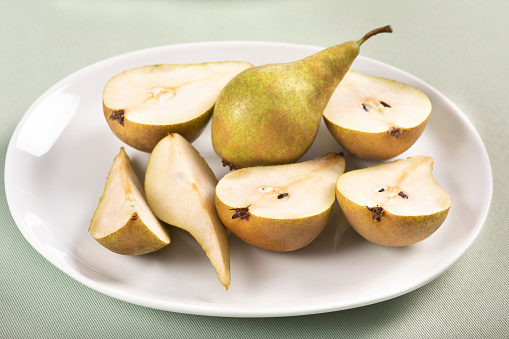 Group of slices pears on white plate and light green tablecloth. The pears are freshly brought from tree.