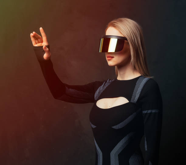 istock Blonde android female in VR glasses and suit on dark background. 1295610912