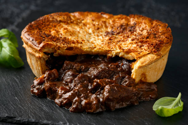 British beef steak pie with onion, wine gravy on rustic stone board British beef steak pie with onion, wine gravy on rustic stone board. savoury pie stock pictures, royalty-free photos & images