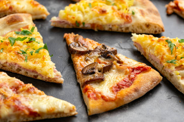istock Slices of pizza with different toppings on black table 1295611622