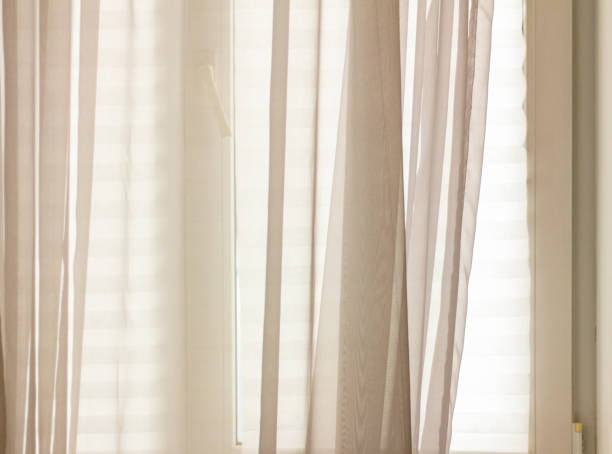 istock A window in a room with drawn blinds and a light veil. 1295617877