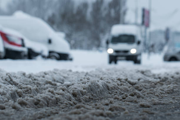 городская парковка с грязной слякотью дороги с парковкой автомобилей в зимнее или весеннее время - sleet стоковые фото и изображения