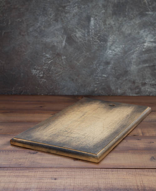 istock Wooden pizza cutting board at table, with wood background texture. Empty wood tray dish for bread food 1295627059