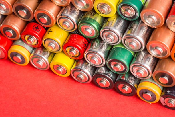 istock Stack of used batteries on a red background 1295628748