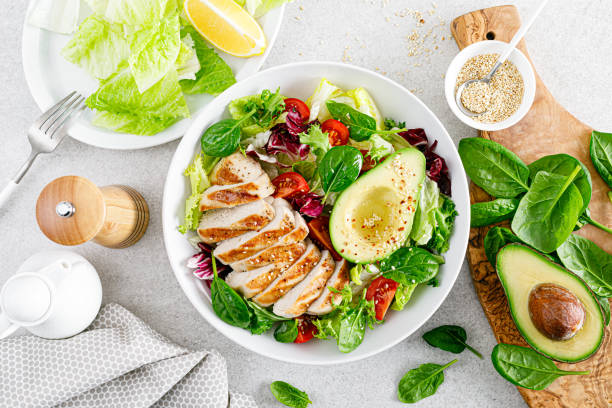 grilled chicken meat and fresh vegetable salad of tomato, avocado, lettuce and spinach. healthy and detox food concept. ketogenic diet. buddha bowl dish on white background, top view - chicken breast chicken grilled chicken protein imagens e fotografias de stock