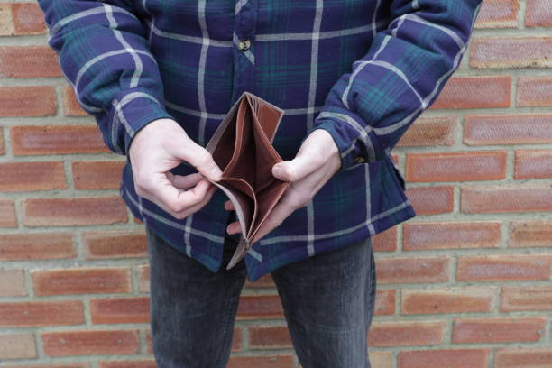 Man with no money showing empty wallet Man with no money showing empty wallet with brick wall behind minimum wage stock pictures, royalty-free photos & images