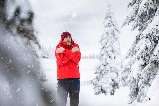 istock Frozen man in a red jacket and hat stands in a forest while snow is falling around 1295632904