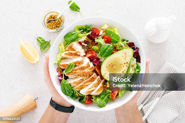 Grilled Chicken Meat And Fresh Vegetable Salad Of Tomato Avocado Lettuce And Spinach Healthy And Detox Food Concept Ketogenic Diet Buddha Bowl In Hands On White Background Top View Stock Photo - Download Image Now