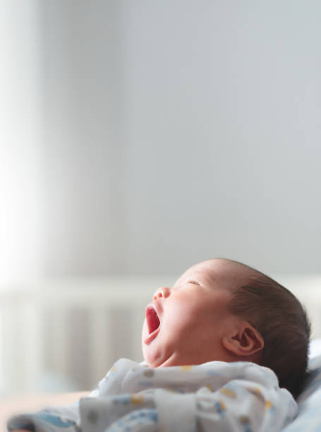 le bébé nouveau-né asiatique mignon bâille après s’être réveillé à la maison. - baby yawning asian ethnicity newborn photos et images de collection