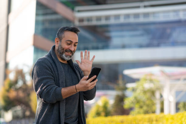 istock Man waving with hand on video call 1295634473