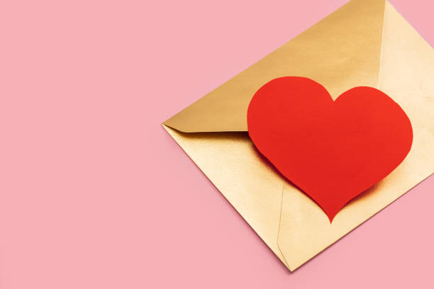 istock Golden paper envelope with red heart isolated on pink background 1295638420