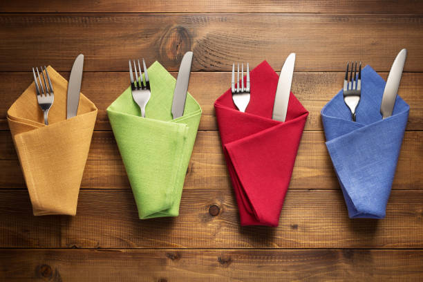 istock knife and fork in folded napkin at rustic wooden plank board table background. Flat lay top view 1295638464