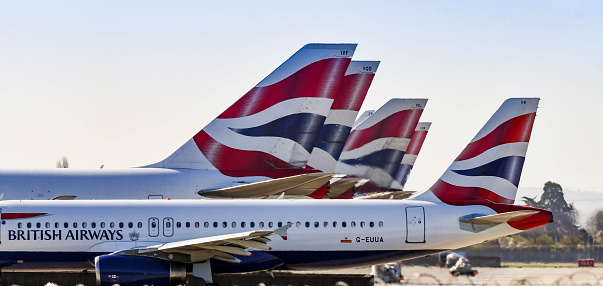 London, England - March 2019: Airbus A320 jet taxiing past the tail fins of the airline's wide body aircraft. The Airbus is used on European routes while the wide bodied aircraft are used on worldwide flights. flights