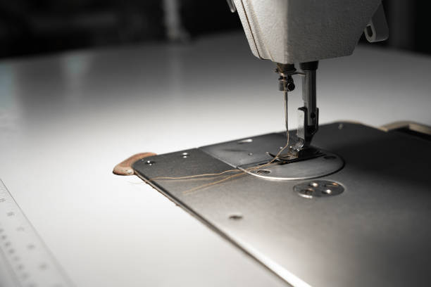 istock Sewing machine and thread in the needle. Atelier for tailoring. Copy space. 1295640117