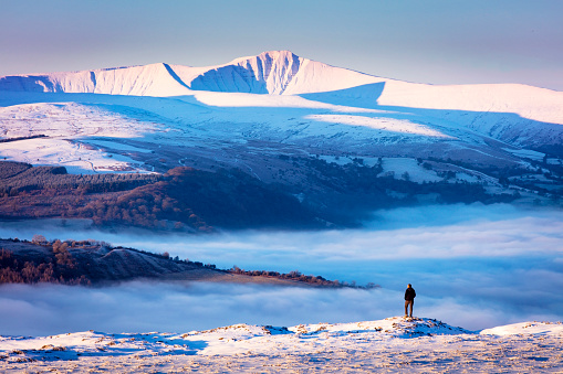 Distant figure below snow capped mountains in the Brecon Beacons national park, Wales