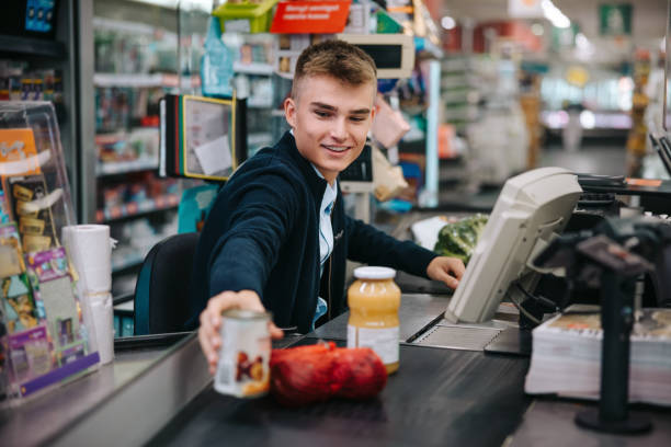 mężczyzna obsługujący klientów przy kasie w supermarkecie - checker zdjęcia i obrazy z banku zdjęć