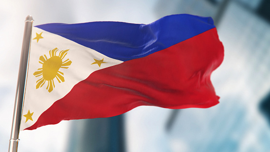 National Flag of Philippines Against Defocused City Buildings