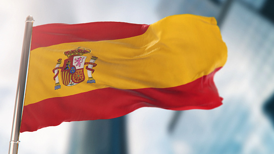 National Flag of Spain Against Defocused City Buildings