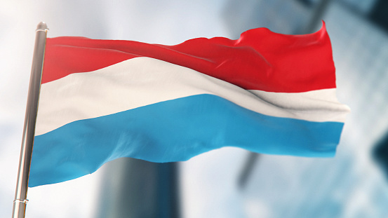 National Flag of Luxembourg Against Defocused City Buildings