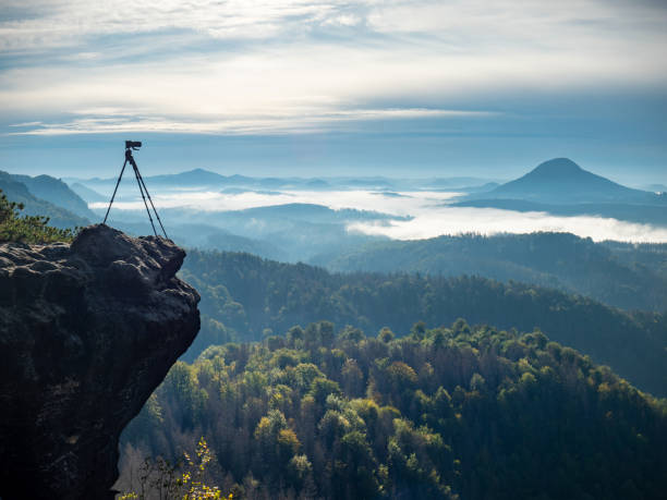 istock Camera on tripod photographing mist in valley 1295645005