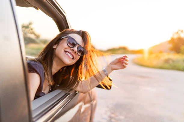 istock Young smiling woman looking through window while riding in car in nature 1295646581