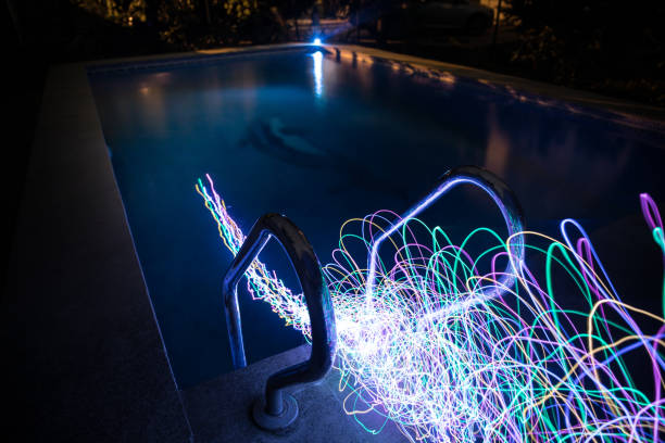 istock Pool and waterfall at night - vacation background. Colorful light decoration. Freezelight 1295647986
