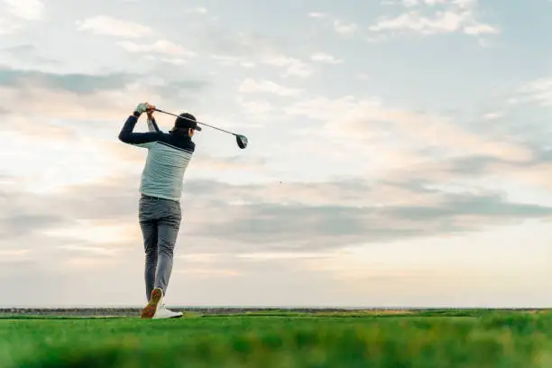 Photo of Sportsman teeing off at course during sunset