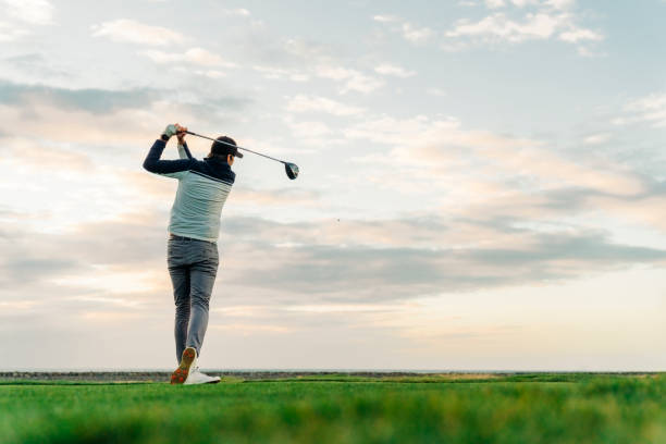 спортсмен teeing покинуть на курс во время заката - golf swing golf teeing off men стоковые фото и изображения