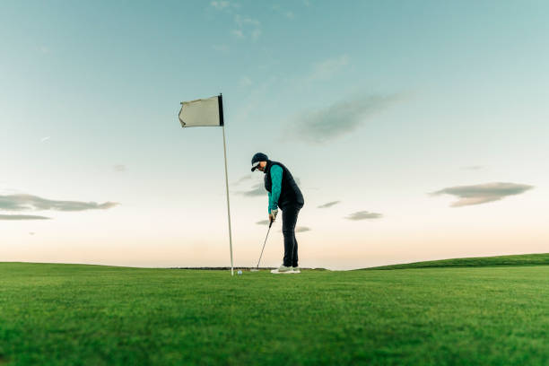donna anziana che oscilla golf club sul campo - golf putting determination focus foto e immagini stock