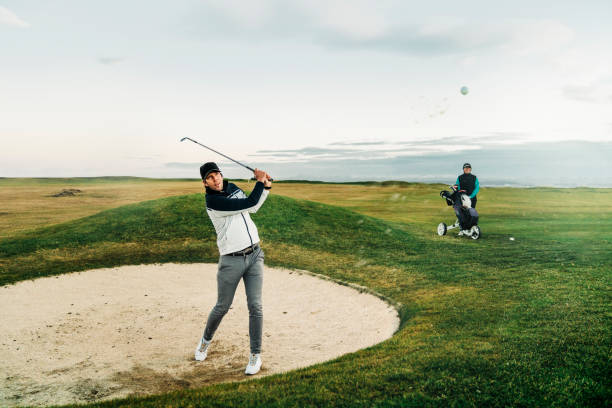 istock Male golfer hitting ball from sand trap at sunset 1295649085