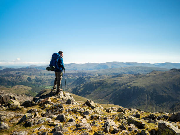 Hiker looking at landscape from mountain summit A hiker views the horizon from Great Gable, a mountain in the Lake District, Cumbria, England. english lake district stock pictures, royalty-free photos & images