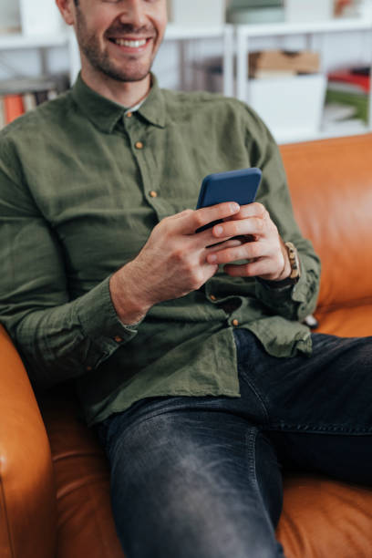 istock Anonymous Smiling Modern Businessman Sitting in the Office and Using his Smartphone to Communicate Online 1295653958