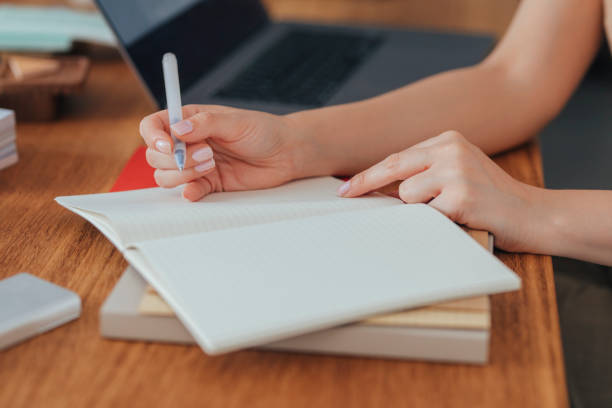 istock Hands of an Anonymous Businesswoman Writing Notes in her Planner 1295653960
