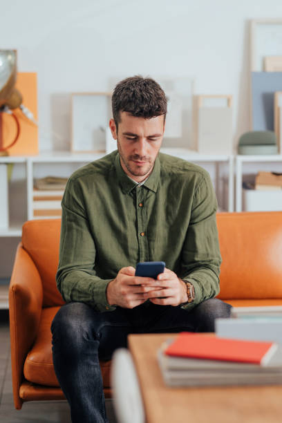 istock Young Modern Businessman Sitting in the Office and Using his Smartphone to Communicate Online 1295653986