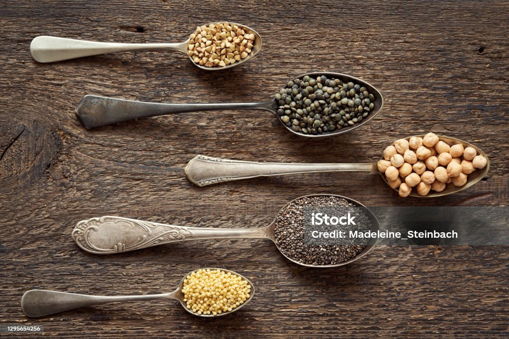 Millet, chia, chickpeas, buckwheat and lentils on five vintage spoons Millet, chia, chickpeas, buckwheat and lentils on five vintage spoons, top view Agriculture Stock Photo