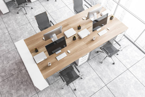 istock Top view of office wooden table with computers, black armchairs on marble floor 1295655336