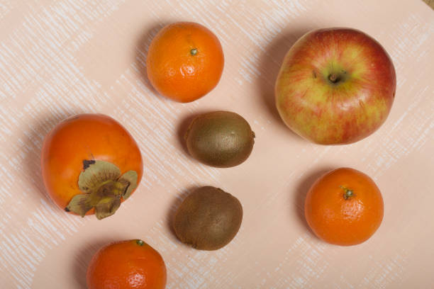 Fruits are scattered on the beige surface. Close-up shot.